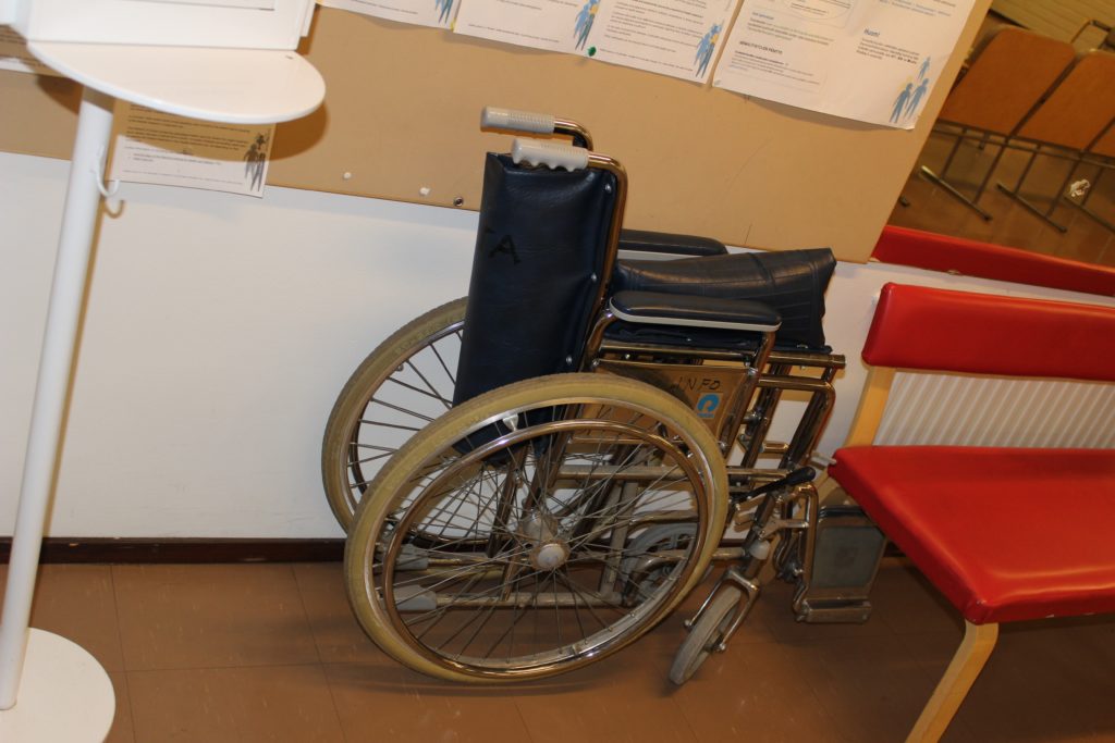Terveyskeskuksen seinää vasten oleva pyörätuoli.
